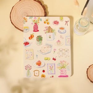 Peut inclure: Un carnet de couleur crème avec une illustration fantaisiste de divers aliments et compositions florales. Le motif comprend des images de pain, de fruits, de fleurs et de pâtisseries, créant une esthétique charmante et artistique.