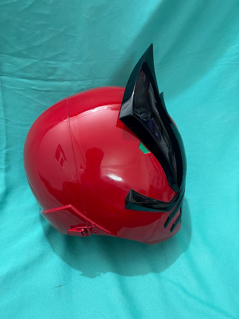May include: A red and black plastic helmet with a pointed crest. The helmet has a glossy finish and is designed to resemble a character from a popular television show.