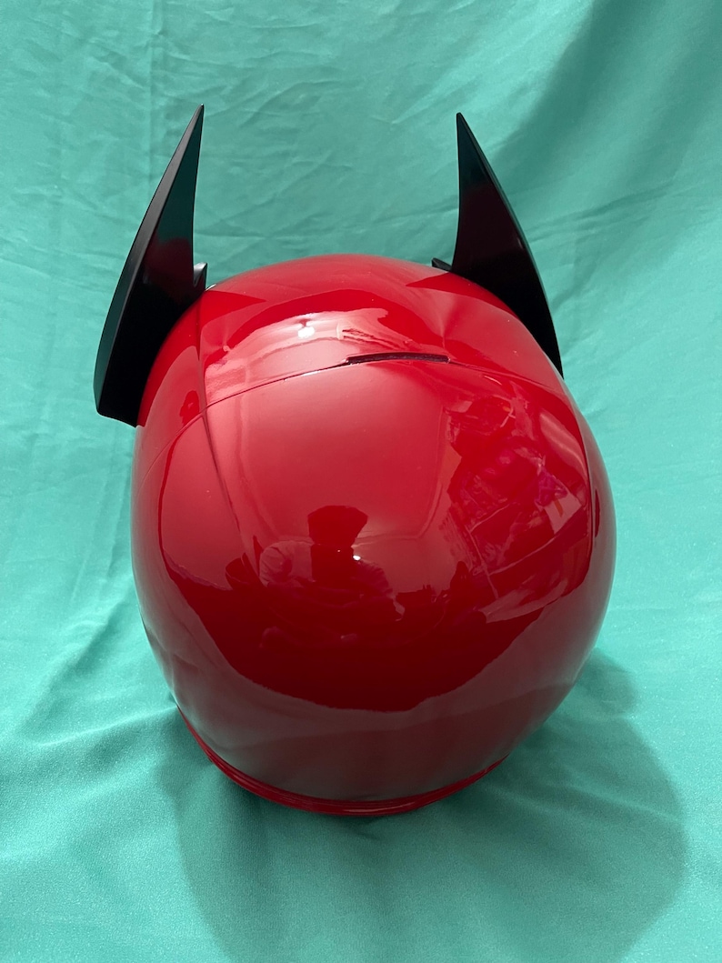 May include: A red motorcycle helmet with black horns attached to the top.