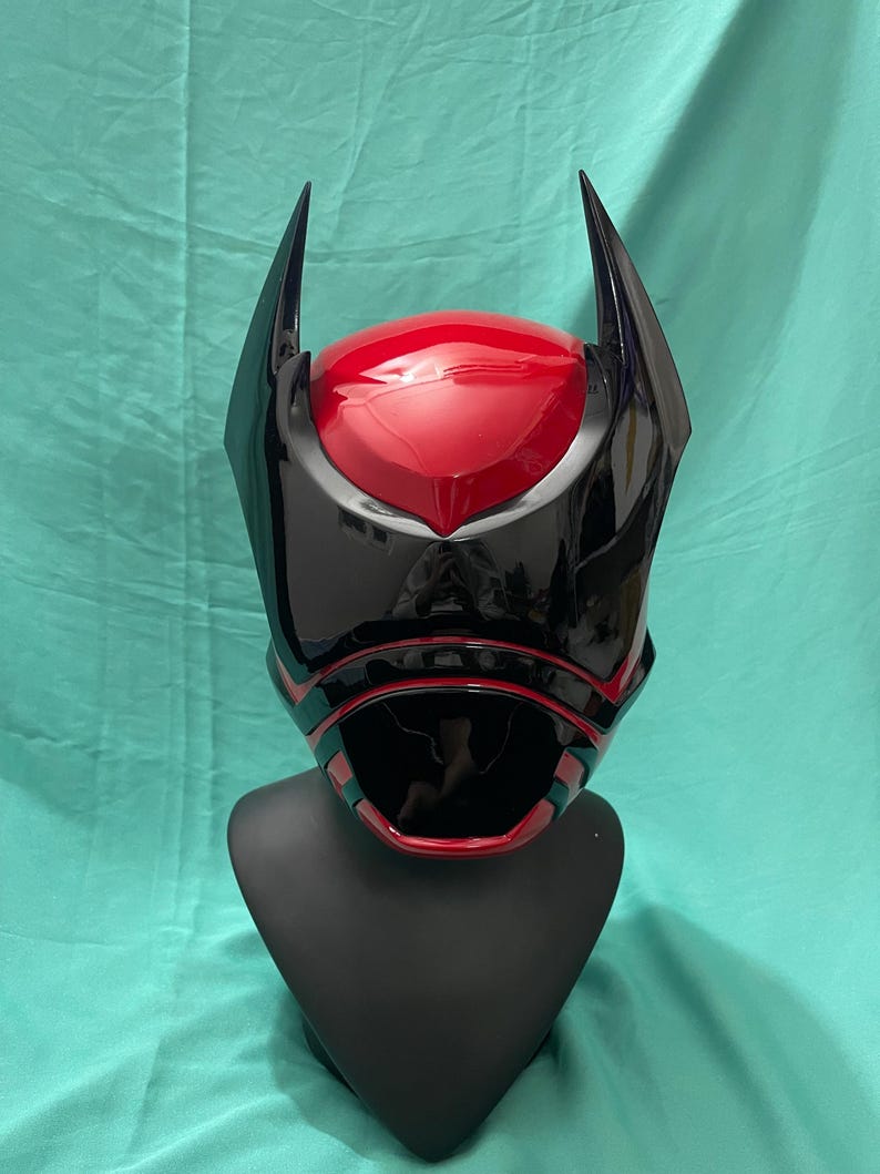 May include: A black and red helmet with a pointed design. The helmet has a black visor and red accents.