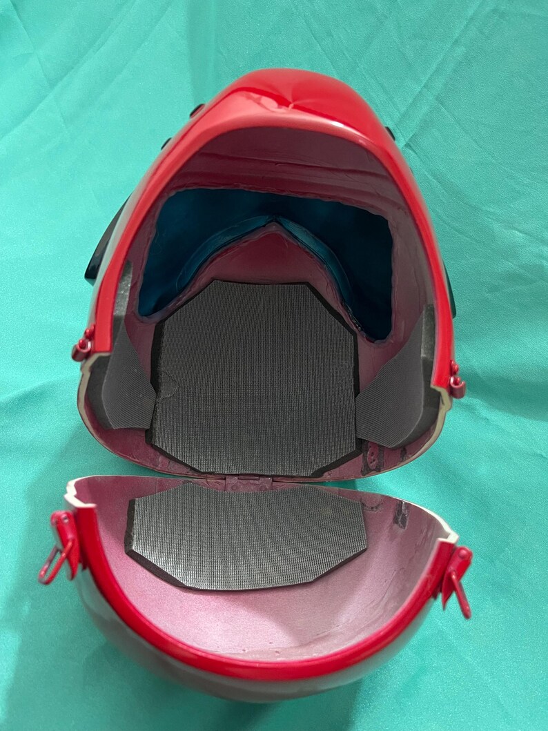 May include: Red helmet with a black trim and a gray interior lining. The helmet is open and the interior is visible.