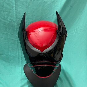 May include: A black and red plastic helmet with a pointed design on the top. The helmet has a black visor and a red interior.