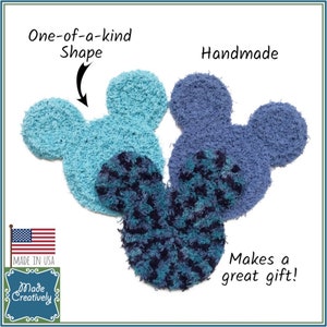 May include: Three handmade, fuzzy, blue and turquoise Mickey Mouse-shaped ornaments. The ornaments are made in the USA and are a great gift. The text "One-of-a-kind Shape" and "Handmade" are written on the image.