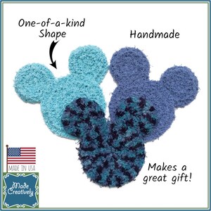 May include: Three handmade, fuzzy, blue and turquoise Mickey Mouse-shaped ornaments. The ornaments are made in the USA and are a great gift. The text "One-of-a-kind Shape" and "Handmade" are written on the image.