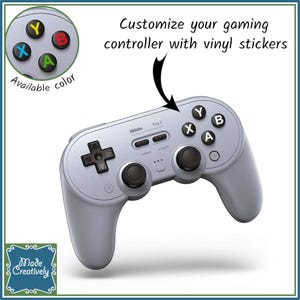 May include: A silver gaming controller with black buttons and a directional pad. The image includes a close-up of colored button stickers and the text "Customize your gaming controller with vinyl stickers."