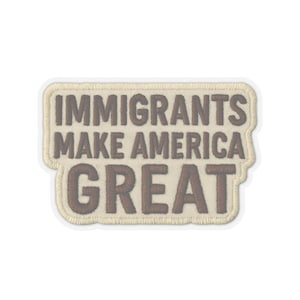 以下が含まれることがあります： 茶色の文字で「IMMIGRANTS MAKE AMERICA GREAT」と刺繍された長方形のパッチ。 パッチはベージュの背景とベージュのボーダーで、白いアウトラインが付いています。
