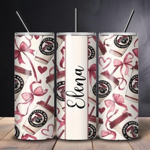 May include: A cylindrical stainless steel tumbler with a straw, featuring a repeating pattern of coffee cups with the Seven Brew logo, pink ribbons, and hearts. A central vertical white panel displays the name Elena in black script lettering.
