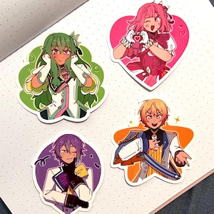 May include: Four anime-style stickers featuring colorful characters. One sticker shows a green-haired character, another a pink-haired character in a heart shape, a third with purple hair, and the last with blonde hair in a star shape.