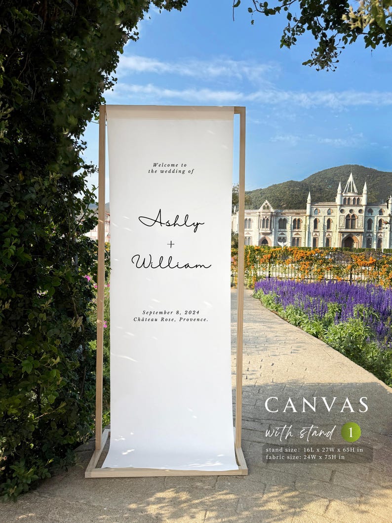 Może przedstawiać: Biały pł&oacute;cienny znak powitalny na wesele z drewnianą ramą. Na znaku widnieje napis "Welcome to the wedding of Ashly + William" i zawiera datę i miejsce. Rozmiar stojaka to 40,6 cm x 68,6 cm x 165,1 cm, a rozmiar materiału to 61 cm x 190,5 cm.