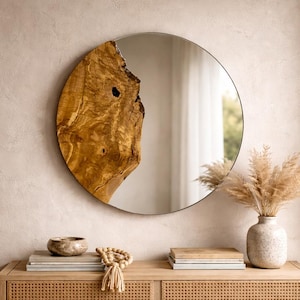 Puede incluir: Un espejo redondo con un acento de madera natural en el lado izquierdo, montado en una pared de color claro. Debajo, una consola de madera con frentes de cajones tejidos exhibe objetos decorativos, incluyendo un jarrón con flores secas.