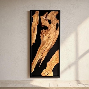 Op de afbeelding: Een rechthoekig wandkunstwerk met natuurlijke houten elementen tegen een zwarte achtergrond in een zwart frame. Het hout is lichtbruin met ingewikkelde nerfpatronen, wat een opvallend contrast creëert.