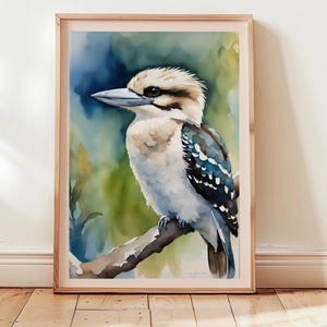 Puede incluir: Pintura acuarela de un kookaburra posado en una rama. El pájaro es azul, blanco y negro con un pico largo. El fondo es una suave acuarela azul y verde.