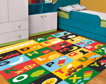 May include: A colorful alphabet play mat with letters, numbers, and illustrations of animals, a house, a train, a key, a pencil, a watermelon, a sun, and a xylophone. The mat is on a wooden floor in a child's bedroom.