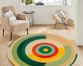 May include: A round area rug with a colorful, abstract design. Concentric circles of green, yellow, red, and beige create a vibrant pattern. The rug is placed on a hardwood floor, with furniture in the background.