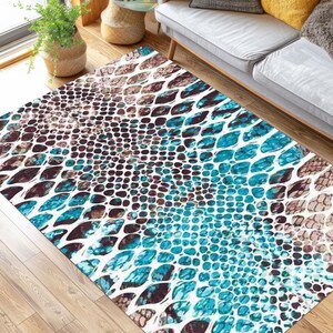 Könnte beinhalten: Ein blauer und brauner Teppich mit Schlangenhautmuster. Der Teppich liegt auf einem Holzboden und vor einem weißen Sofa.