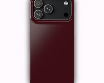 Puede incluir: Una funda para smartphone de color burdeos intenso con una parte trasera lisa y sólida. La sección superior presenta un recorte rectangular negro para el módulo de cámara, con tres aberturas circulares y un flash a la derecha.