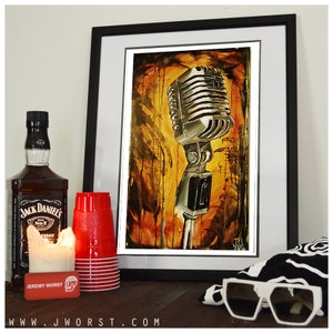 May include: A framed painting of a vintage microphone with a yellow, orange, and brown background. The microphone is silver and has a black stand. The painting is framed in black and has a white mat.