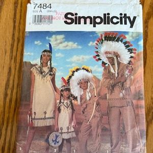 May include: A Simplicity 7484 sewing pattern envelope for costumes. The front features an illustration of four people wearing tan fringed outfits with feathered headdresses and accessories, set against a desert landscape background.
