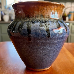 May include: A blue and brown ceramic vase with a textured surface and black glaze dripping down the sides.