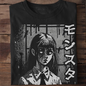 May include: Black and white graphic t-shirt featuring a girl with blood dripping from her eyes and mouth. The girl is wearing a white shirt with a black tie. The background is a gray brick wall with barbed wire. The text "生ける屍" is written in Japanese on the right side of the shirt.