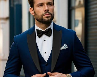 May include: A man wearing a dark blue tuxedo with a black satin lapel, a white dress shirt, a black bow tie, and a white pocket square. The tuxedo has a matching vest. The man is wearing a gold watch on his left wrist.