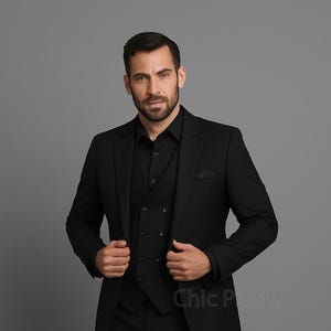 Puede incluir: Un traje negro de tres piezas, que incluye una americana, un chaleco y una camisa. El traje es de color negro liso y se lleva con una camisa negra. La imagen está sobre un fondo gris.