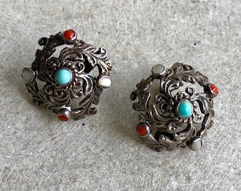 May include: A pair of silver earrings with intricate floral designs. Each earring features turquoise and coral stones.