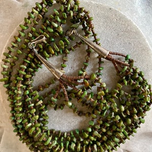 May include: A multi-strand necklace made of green turquoise stones and brown beads. The necklace has silver clasps and accents.