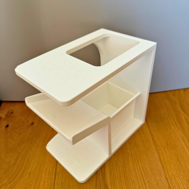 May include: White plastic organizer with three compartments and a top shelf. The top shelf has a cutout for a phone or other device. The organizer is labeled "Organize Your Life" on the top shelf.