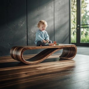 May include: A contemporary, curved wooden bench with a dark brown finish. The bench has a distinctive, flowing design. A child is sitting on the bench playing with colourful blocks. The bench is placed on a hardwood floor.