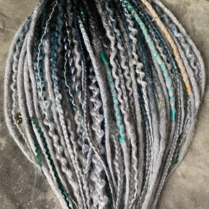 Bohemian grey ombre dreads with emerald accents and stylish hair accessories