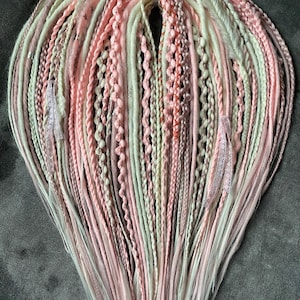 Smooth dreadlocks braids in soft pink, peach tones. Festival style.