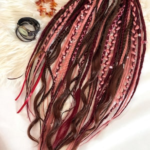 Double-ended dreadlocks in natural shades of chocolate, burgundy, and smoky rose.