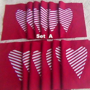 May include: Two sets of red fabric placemats with white striped hearts. The top set has three hearts and the bottom set has four hearts. The text "Set A" is printed on the fabric.
