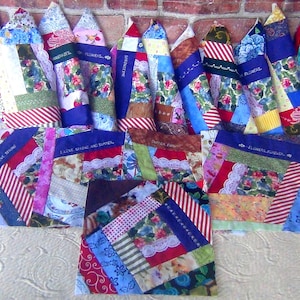 May include: A collection of rectangular and triangular fabric quilt blocks featuring a patchwork of various colorful patterns, floral prints, stripes, and white lace trim. Several blocks include embroidered text such as I LOVE SEWING and FLOWERS FOREVER.