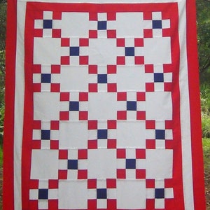 May include: A red, white, and blue quilt top with a geometric pattern. The quilt top is hanging on a clothesline.