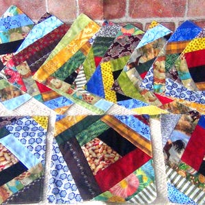 May include: A collection of colorful, handmade fabric coasters. Each coaster features a unique patchwork design with various patterns, including floral, animal prints, and geometric shapes. The coasters are arranged on a light-colored surface.