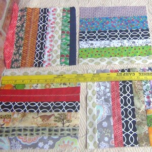 May include: A patchwork quilt block made of colorful fabric strips. The block is made up of 10 rows of fabric strips, each row with a different pattern. The fabric strips are sewn together to create a patchwork design. The block is approximately 12 inches by 12 inches.
