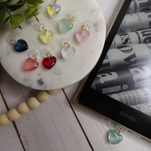 May include: Assortment of colorful heart-shaped charms with gold accents. The charms are made of glass and have a variety of colors, including red, pink, blue, green, yellow, and clear. The charms are hanging from a clear string and are perfect for adding a touch of whimsy to any project.