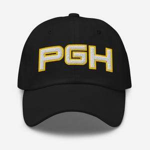 以下が含まれることがあります： 黒い野球帽。白い文字「PGH」が黄色の縁取りで刺繍されています。つばはカーブしており、後ろに布製のストラップ留めが付いています。