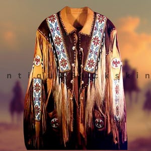 Peut inclure: Veste en cuir marron avec des franges beiges et des broderies complexes rouges, blanches et bleues. La veste présente un col et des écussons décoratifs avec un motif amérindien. Le texte "Antique Buckskin" est visible.