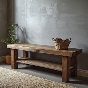 May include: A rectangular wooden bench with a dark brown finish, featuring four thick block legs and a lower storage shelf. A round, woven wicker basket filled with brown pinecones sits on the top surface of the bench.