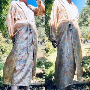 May include: A long-sleeved robe in a pale peach hue featuring a repeating floral pattern in shades of blue, red, and orange. The garment includes a shawl collar, long sleeves with cuffs, and a matching fabric tie belt at the waist.