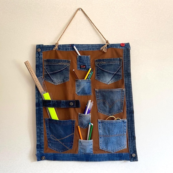 Organiseur mural en denim recyclé : poches en jean suspendues à la main