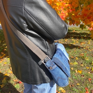 Upcycled denim messenger bag with striped design, adjustable strap, black nylon lining, and 2 interior pockets.