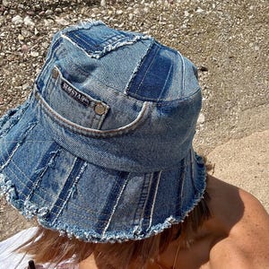 Op de afbeelding: Een blauwe denim bucket hat met een rafelige rand en een aangehechte patch met de tekst "SEMSTAR".