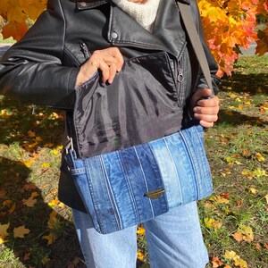 Upcycled denim messenger bag with striped design, adjustable strap, black nylon lining, and 2 interior pockets.