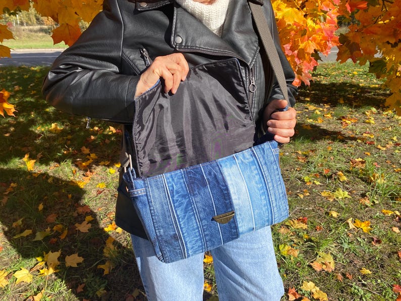 Upcycled denim messenger bag with striped design, adjustable strap, black nylon lining, and 2 interior pockets.