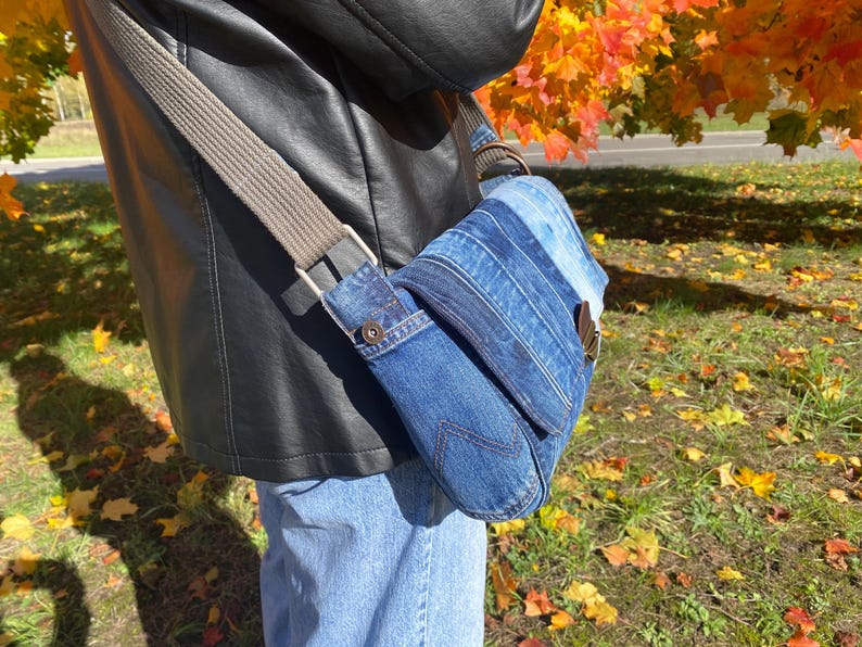 Upcycled denim messenger bag with striped design, adjustable strap, black nylon lining, and 2 interior pockets.
