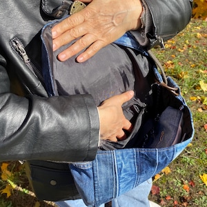 Upcycled denim messenger bag with striped design, adjustable strap, black nylon lining, and 2 interior pockets.